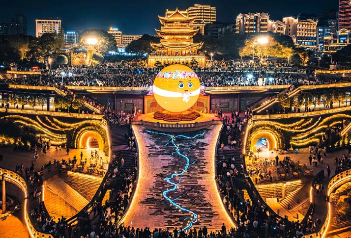 Wide panorama view of riverside plaza with spherical LED landmark playing emoji visual effects