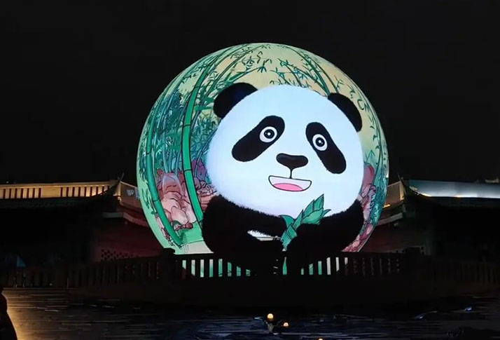 360‑degree outdoor spherical LED screen playing cartoon panda animation at city riverside plaza